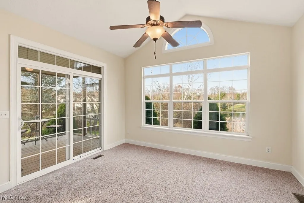 Sun room with vaulted ceiling, light colored carpet, and ceiling fan