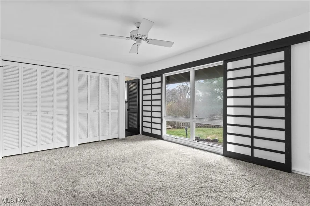 Unfurnished bedroom featuring two closets, light colored carpet, and ceiling fan