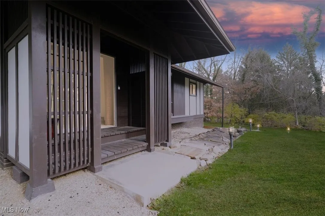 Doorway to property featuring a yard, a patio area, and board and batten siding