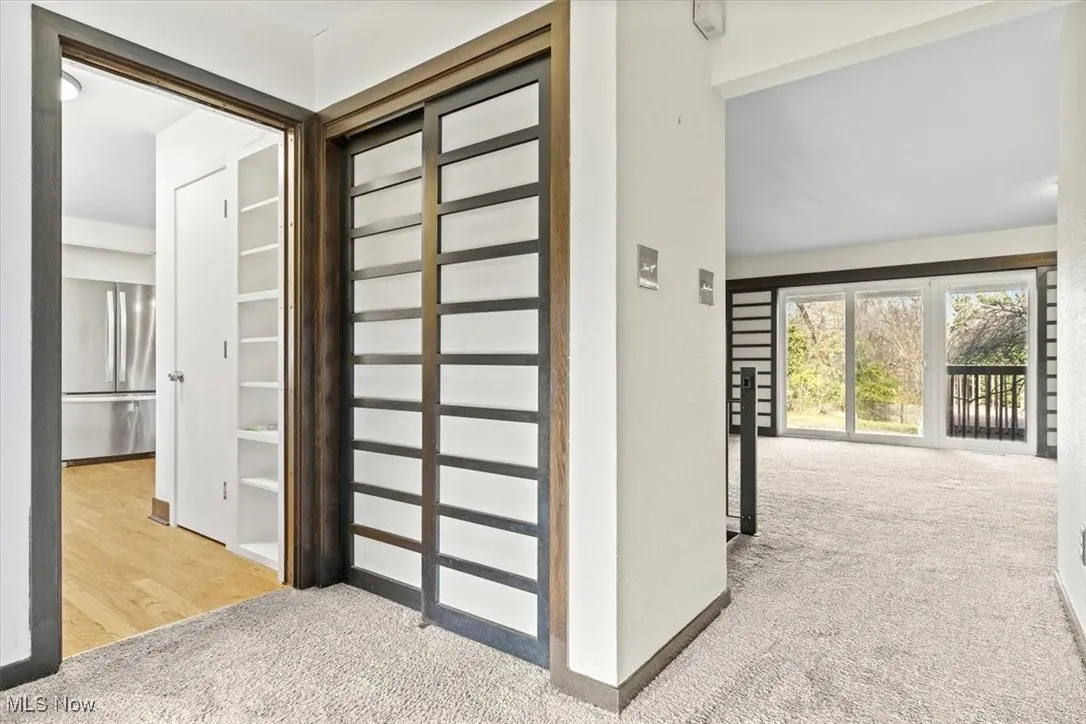 Corridor featuring light carpet and baseboards