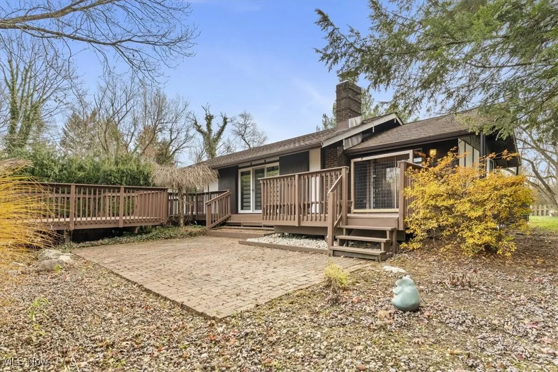 Rear view of property with a deck, a chimney, and a shingled roof