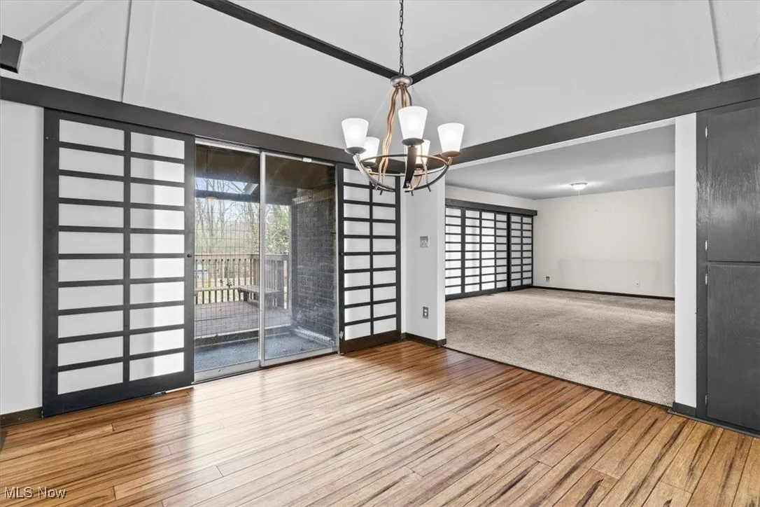 Unfurnished dining area featuring light wood finished floors, a chandelier, and expansive windows
