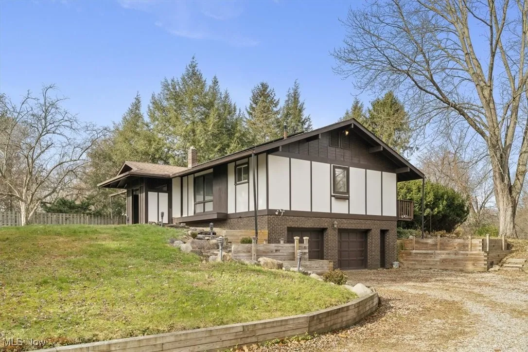 View of side of home with board and batten siding, driveway, brick siding, and a garage