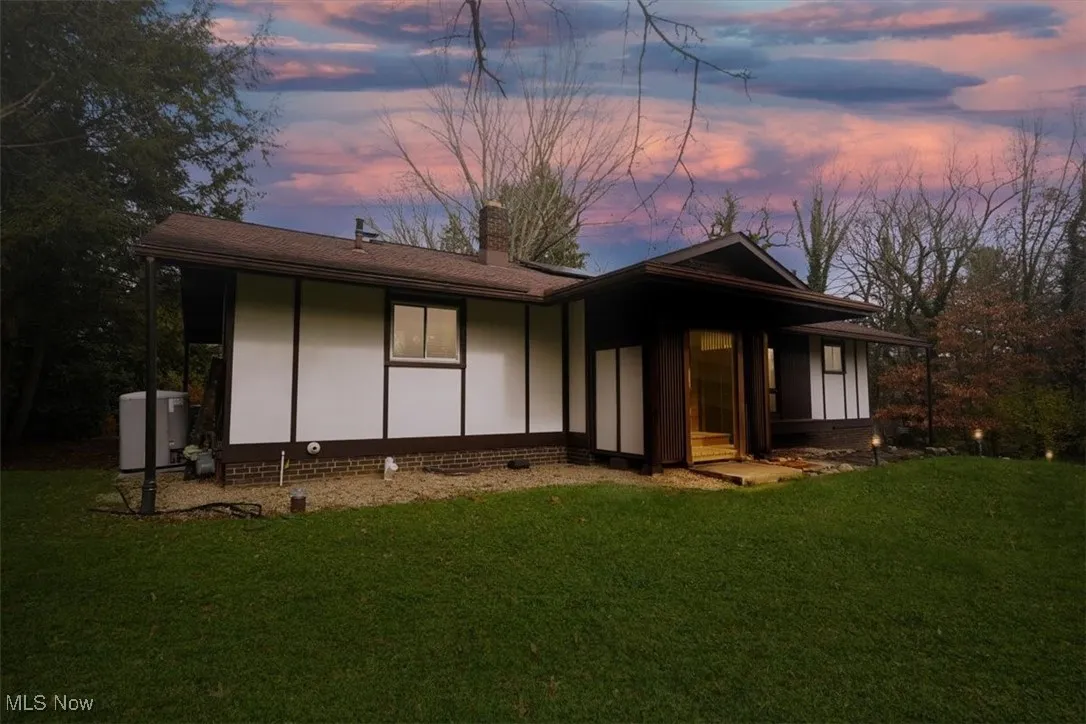 View of front of home with a lawn, a chimney, and board and batten siding