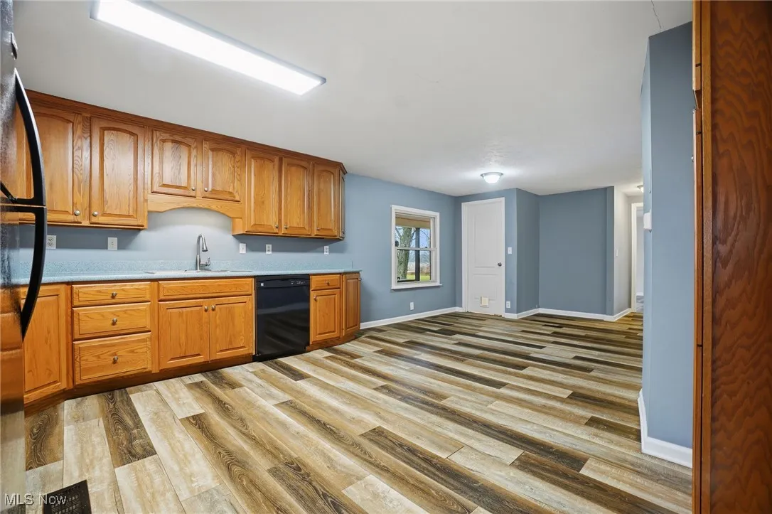 Kitchen featuring brown cabinets, black appliances, and light wood finished floors