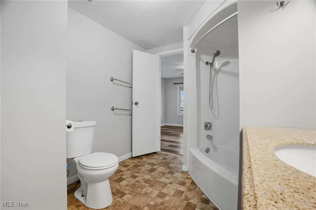 Bathroom featuring shower / tub combination, vanity, and a textured ceiling