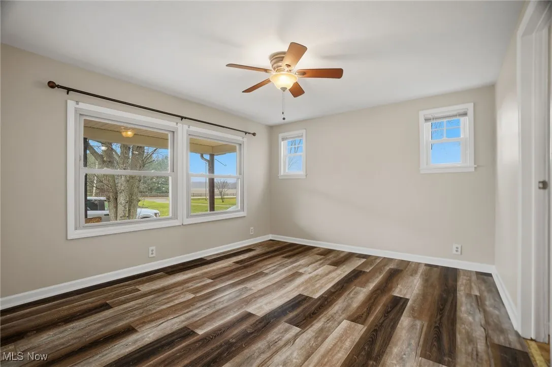 Spare room featuring dark wood finished floors and ceiling fan
