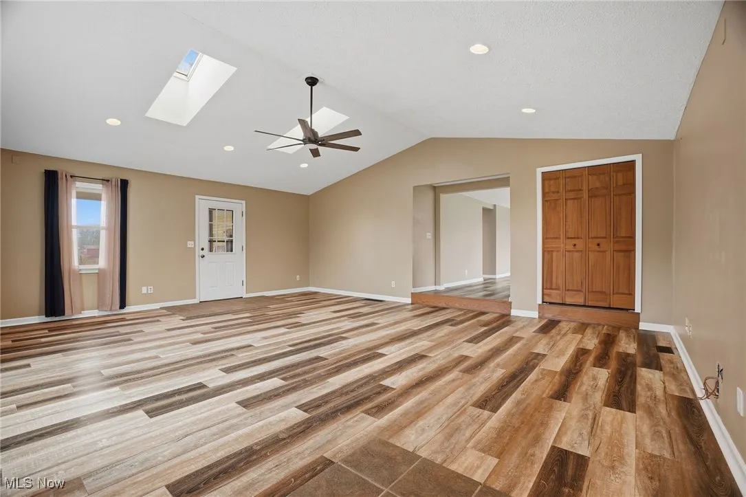 Spare room with light wood finished floors, vaulted ceiling, recessed lighting, a ceiling fan, and a skylight