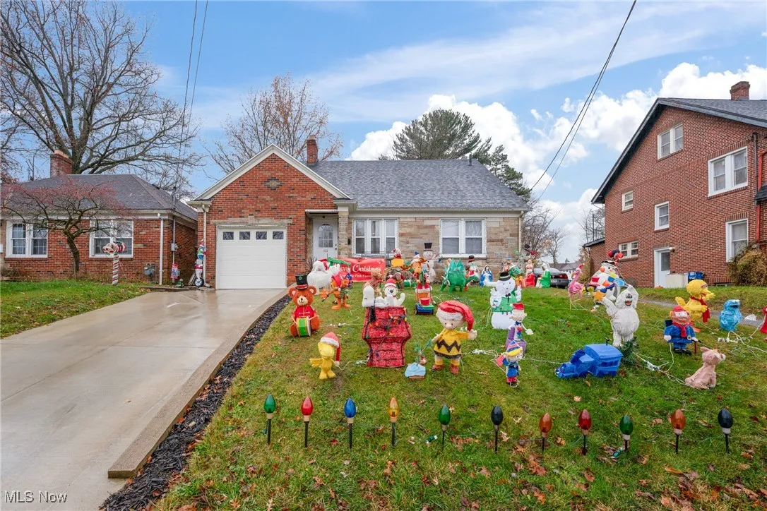 View of front of home with concrete driveway, a chimney, an attached garage, and brick siding