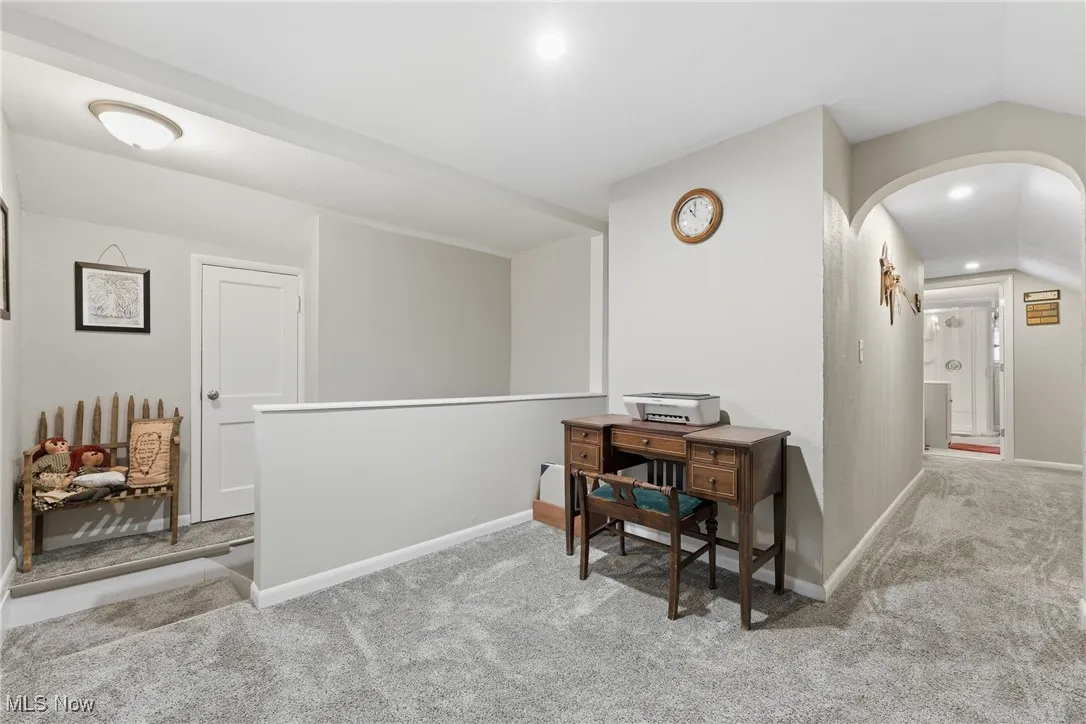 Hall with carpet flooring, lofted ceiling, arched walkways, an upstairs landing, and recessed lighting