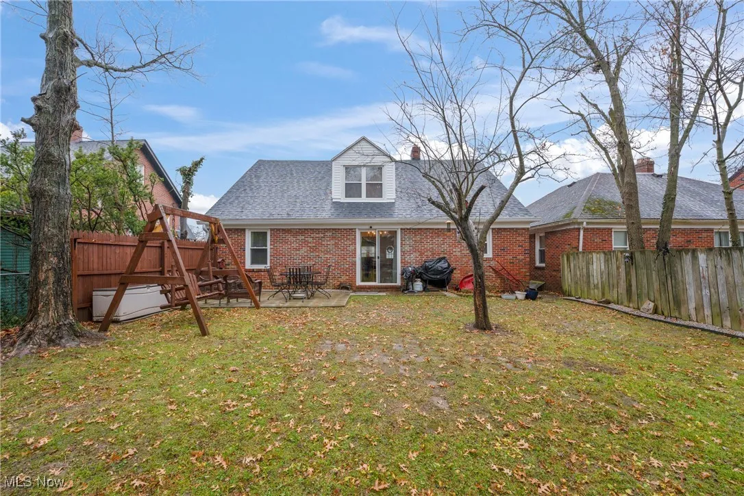 Back of property with a fenced backyard, brick siding, a patio, and a shingled roof