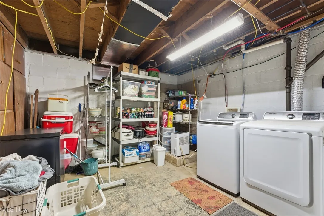 Unfinished basement featuring washing machine and dryer and black refrigerator