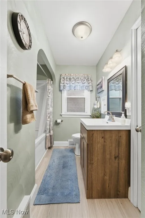 Bathroom featuring vanity, shower / bath combo with shower curtain, and light wood-style floors