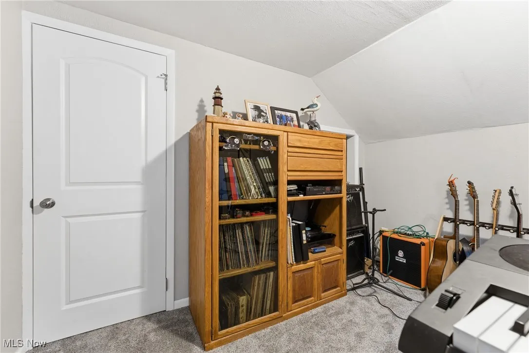 Home office with vaulted ceiling and light carpet