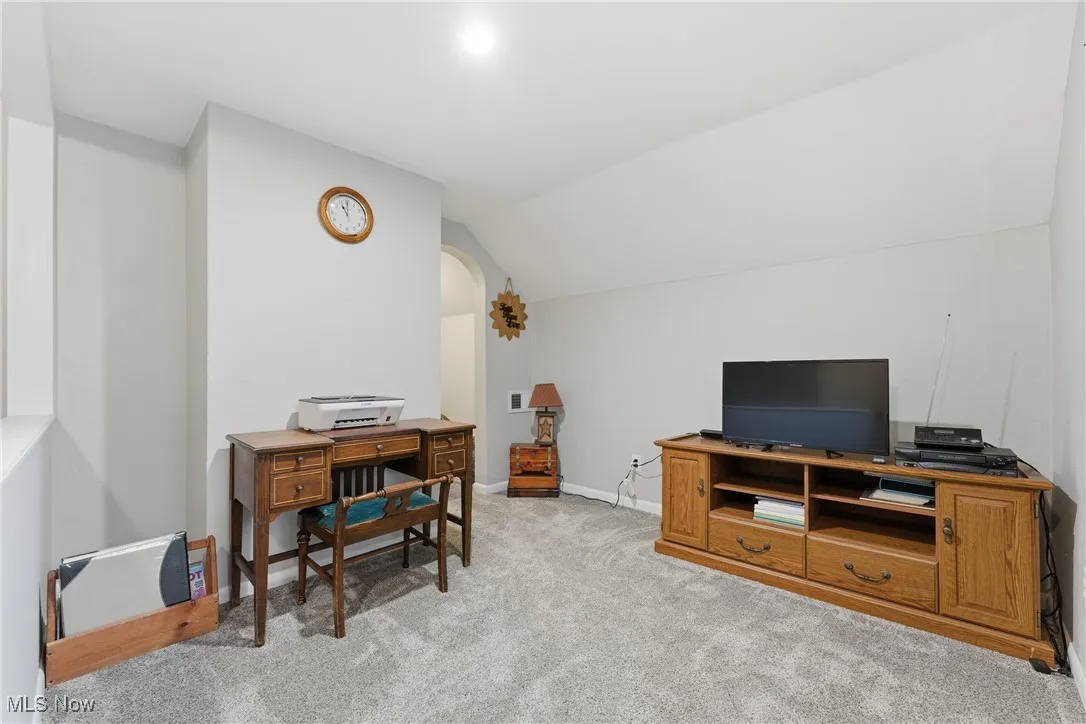 Office with vaulted ceiling and light colored carpet