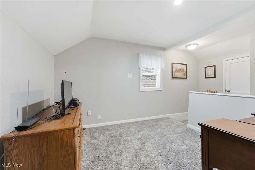 Office space with vaulted ceiling and light colored carpet