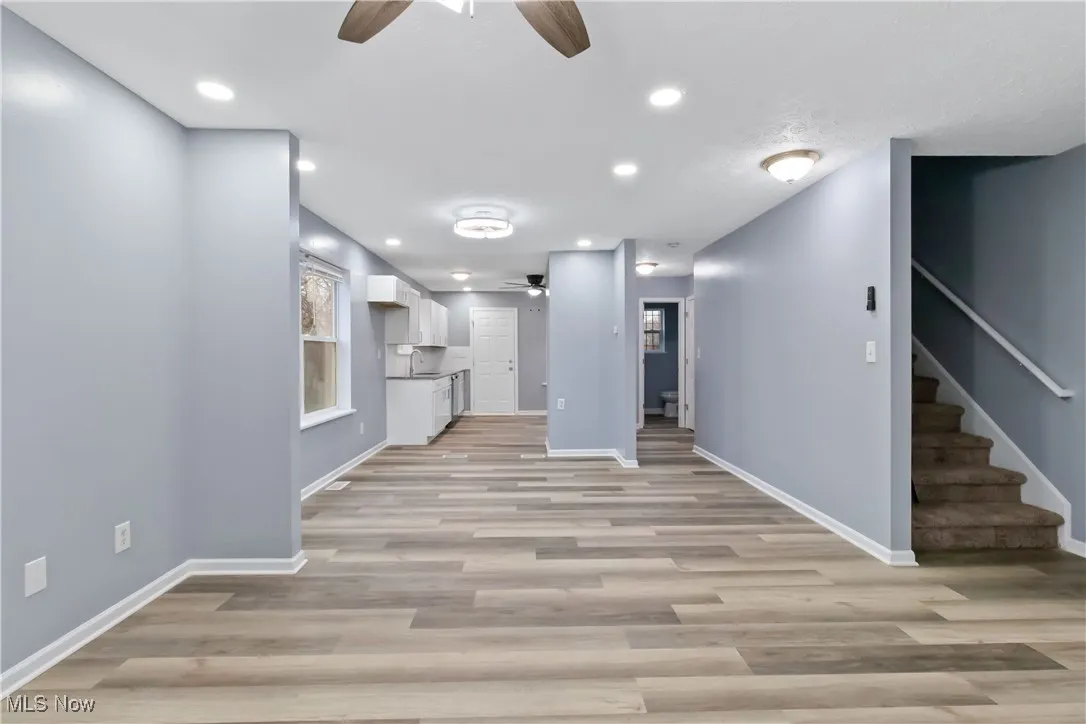 Unfurnished living room with ceiling fan, recessed lighting, light wood-type flooring, and stairway