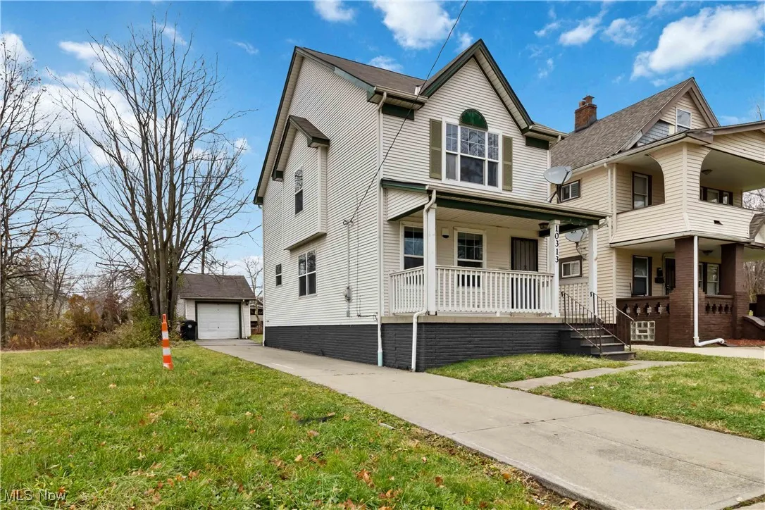View of front facade featuring a porch, an outdoor structure, a front yard, and driveway