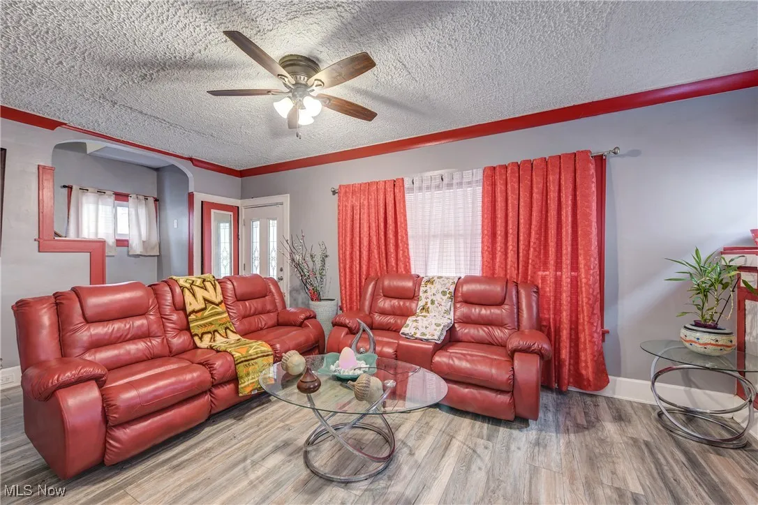 Living room with wood finished floors, a textured ceiling, and ceiling fan