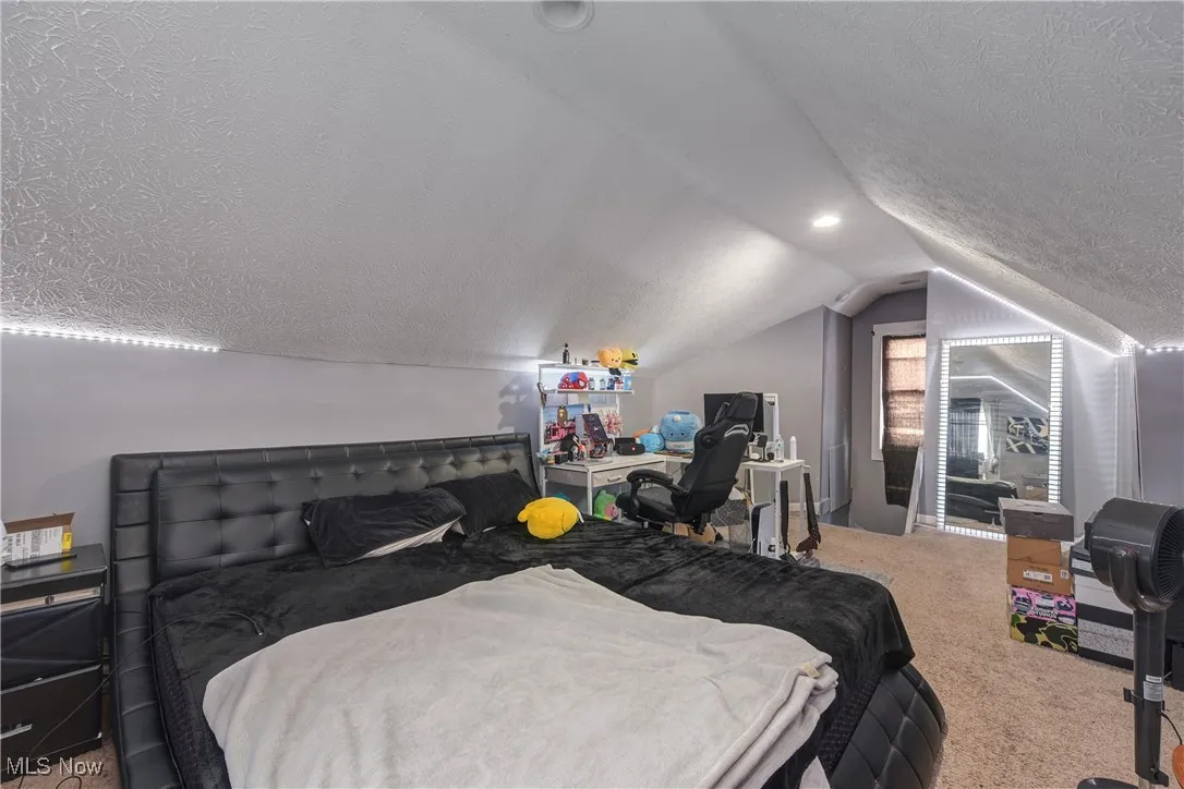 Bedroom featuring carpet, a textured ceiling, and lofted ceiling