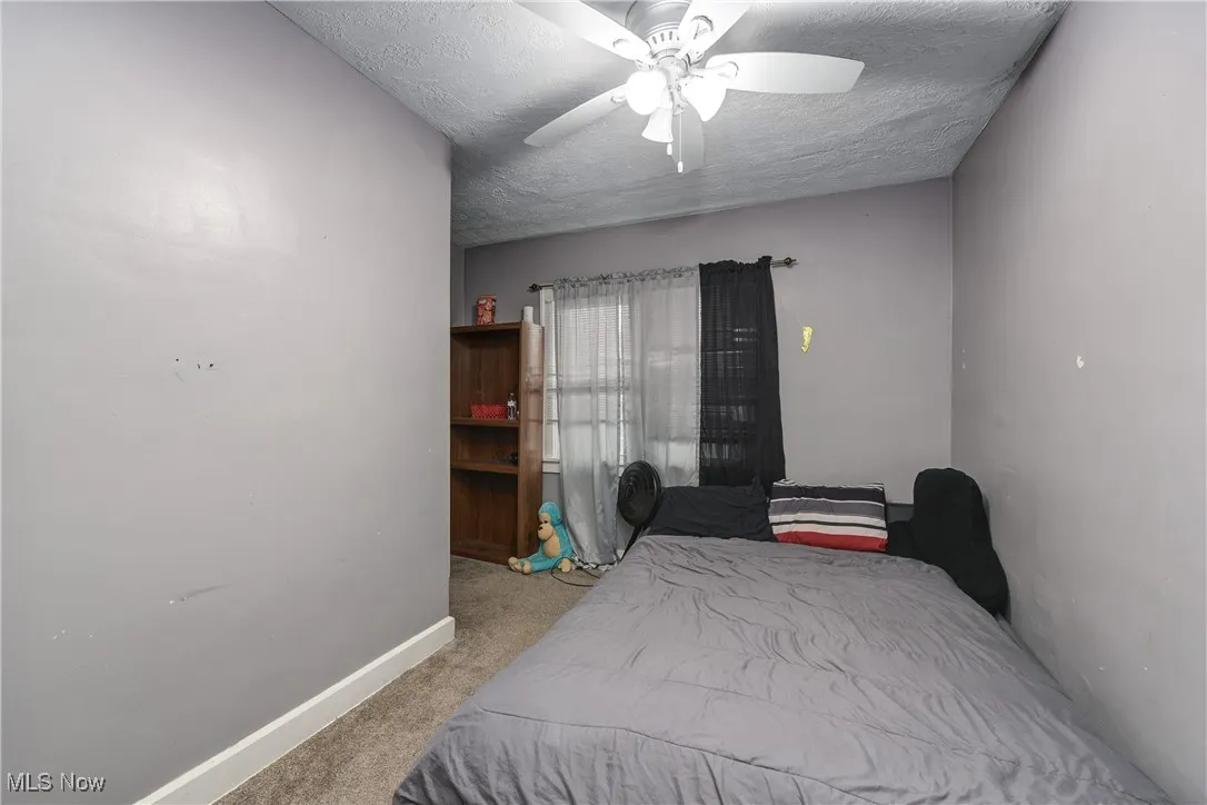Bedroom with light colored carpet, a textured ceiling, and ceiling fan