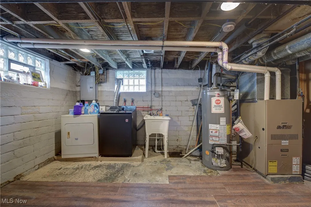 Basement featuring water heater, independent washer and dryer, electric panel, and heating unit