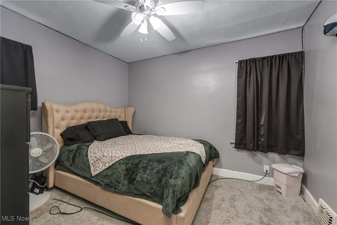 Carpeted bedroom with ceiling fan and baseboards