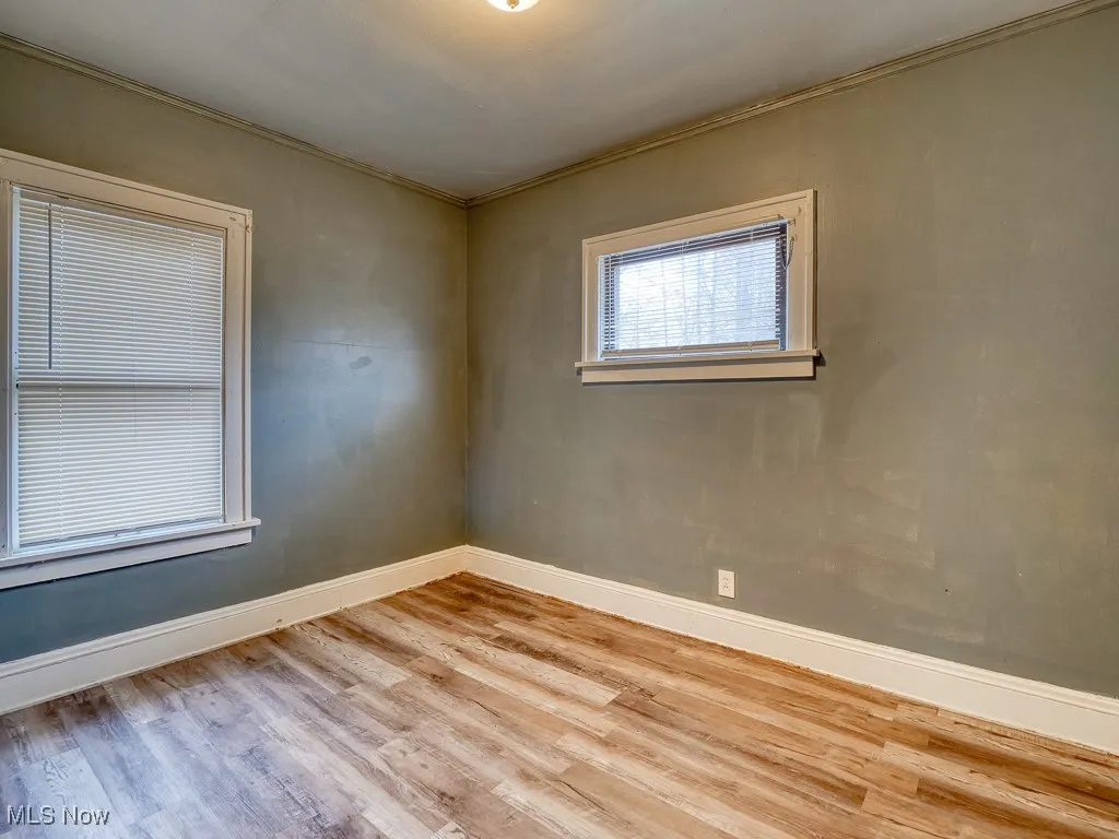 Empty room with baseboards and light wood-type flooring