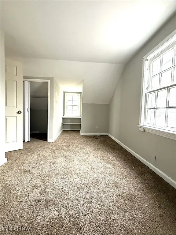 Additional living space with lofted ceiling and carpet floors