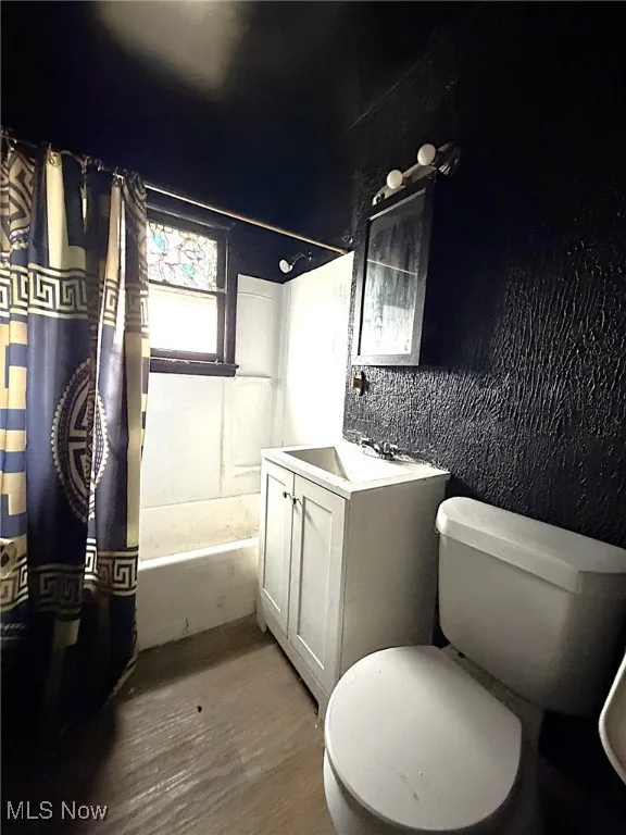 Full bathroom with shower / tub combo with curtain, vanity, and wood finished floors