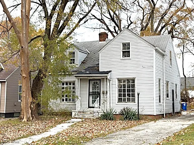 Cape cod home with a chimney and a shingled roof