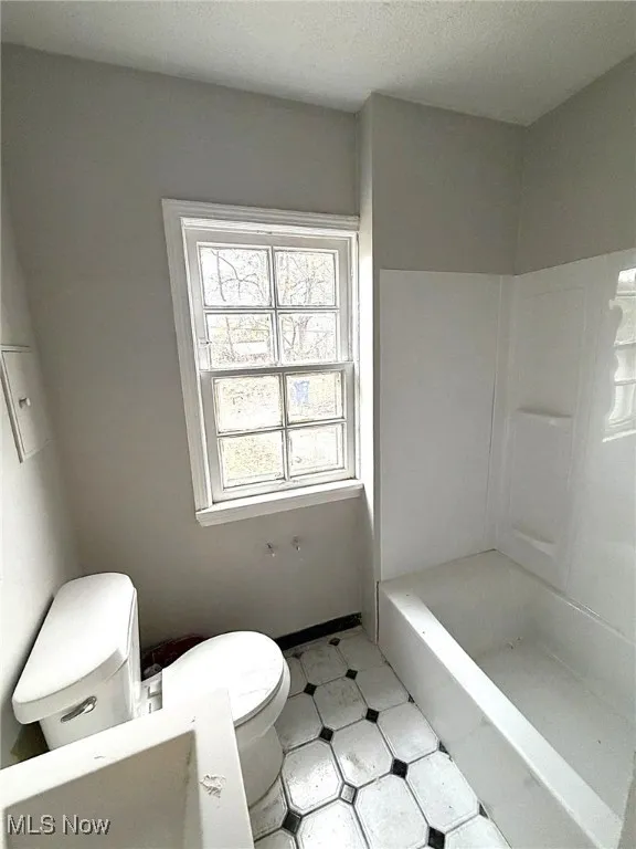 Full bath featuring a textured ceiling, tile patterned floors, and shower / washtub combination