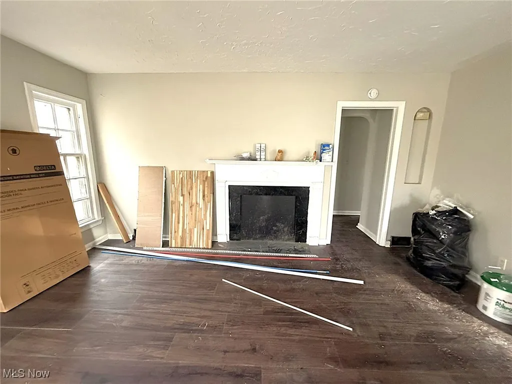 Living area featuring a fireplace, dark wood-type flooring, a textured ceiling, and a heating unit