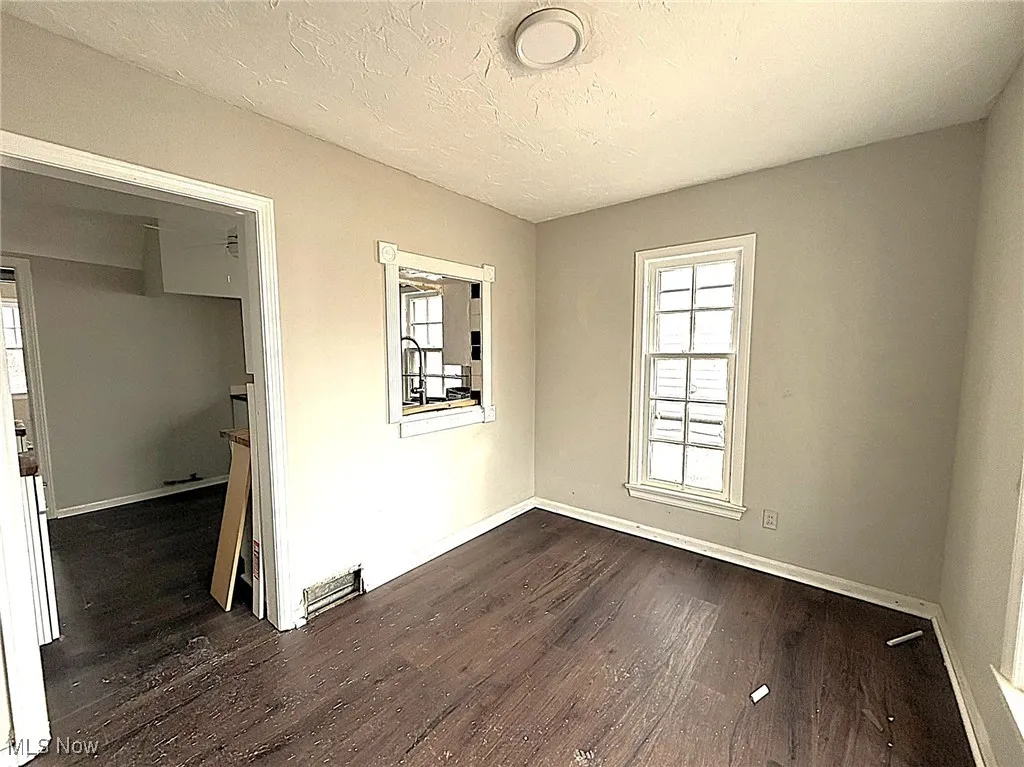 Unfurnished room featuring dark wood-type flooring and a textured ceiling