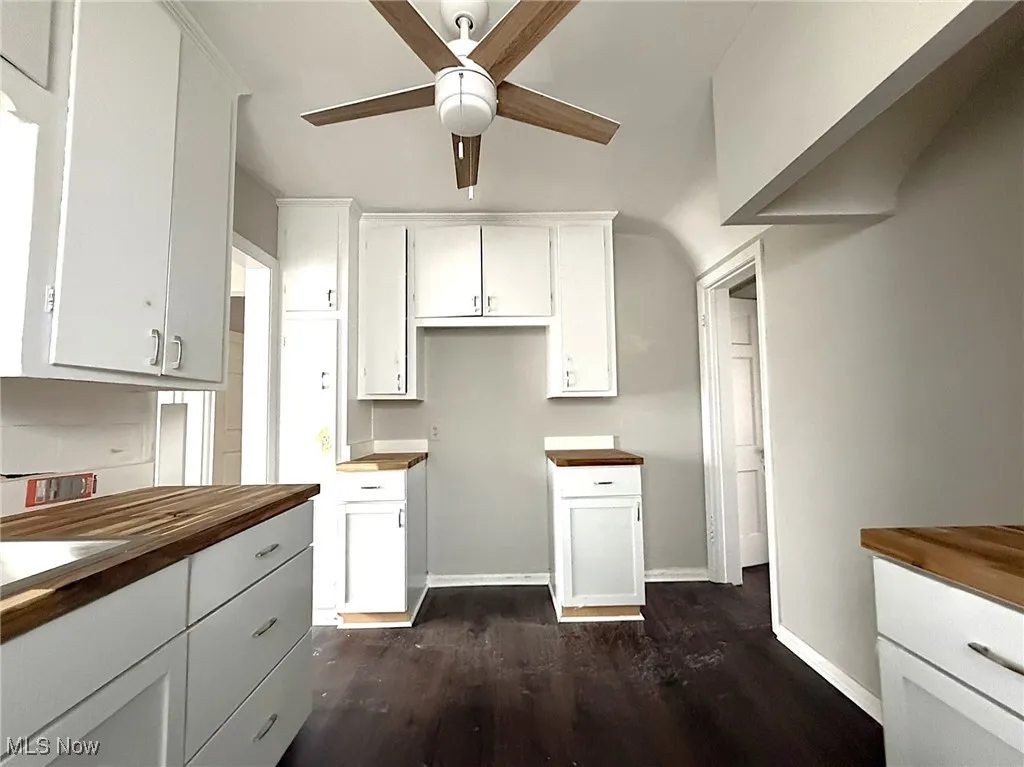 Kitchen featuring white cabinetry, dark wood-style floors, a ceiling fan, and butcher block countertops