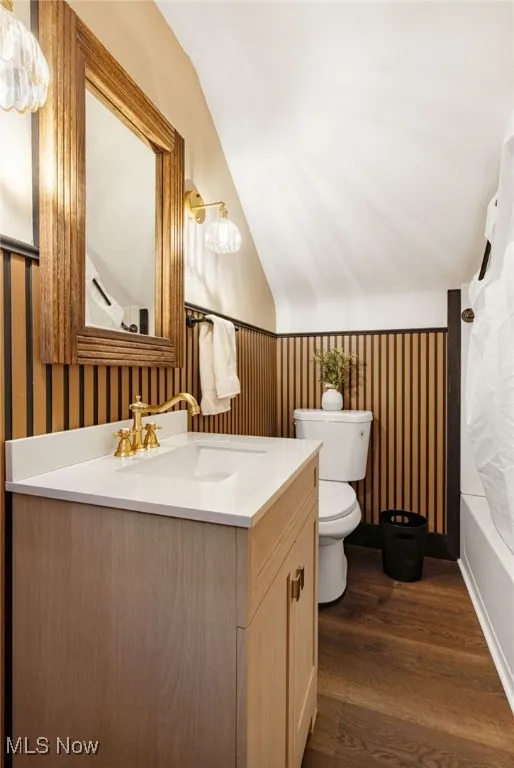 Bathroom featuring vanity, dark wood-type flooring, vaulted ceiling, and shower / bath combo with shower curtain