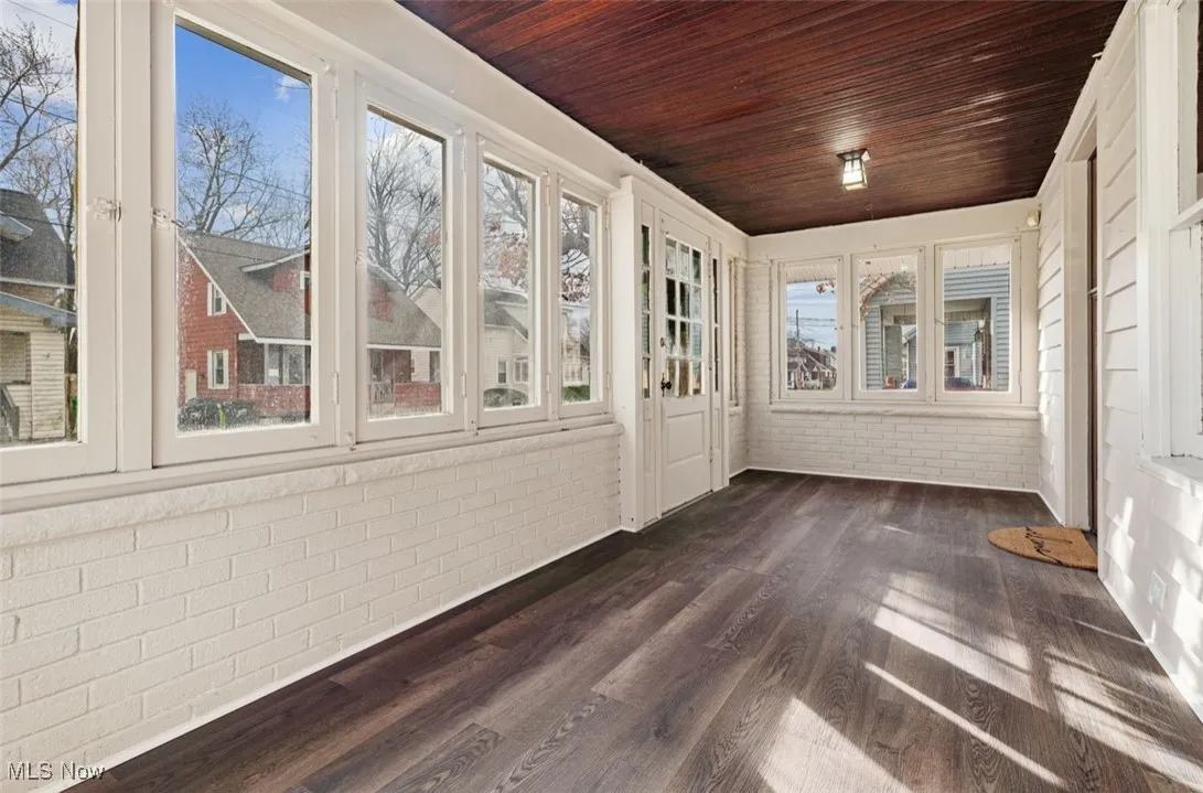 Unfurnished sunroom featuring brick wall, wood finished floors, and wood ceiling