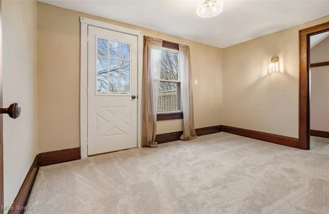 Empty room with light colored carpet and baseboards