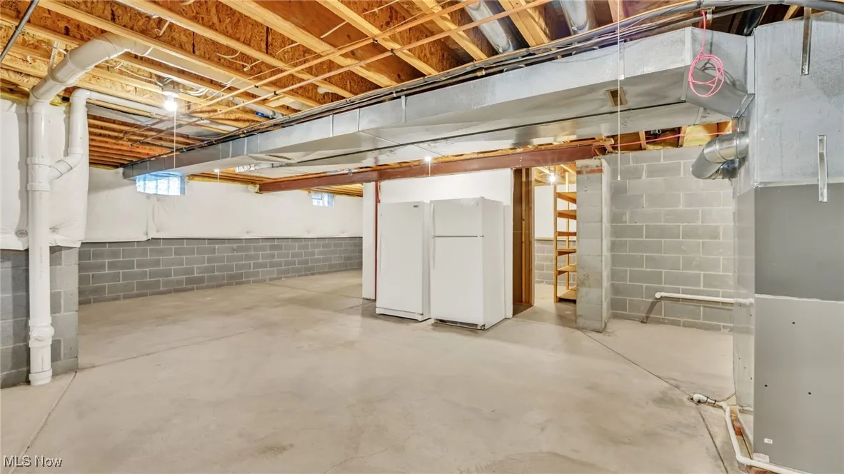 Basement with freestanding refrigerator, freezer and heating unit