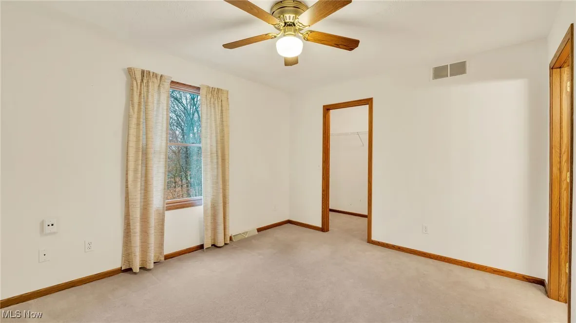 Carpeted bedroom featuring a walk in closet and a ceiling fan