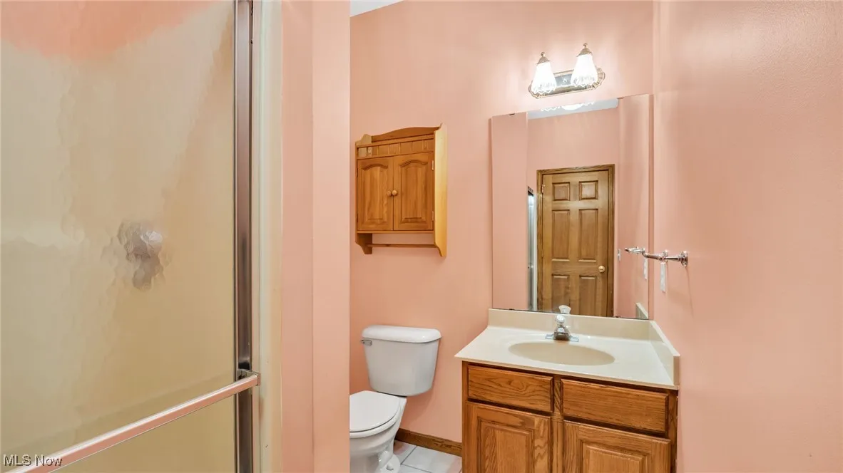 Bathroom featuring vanity, a shower stall, and light tile flooring
