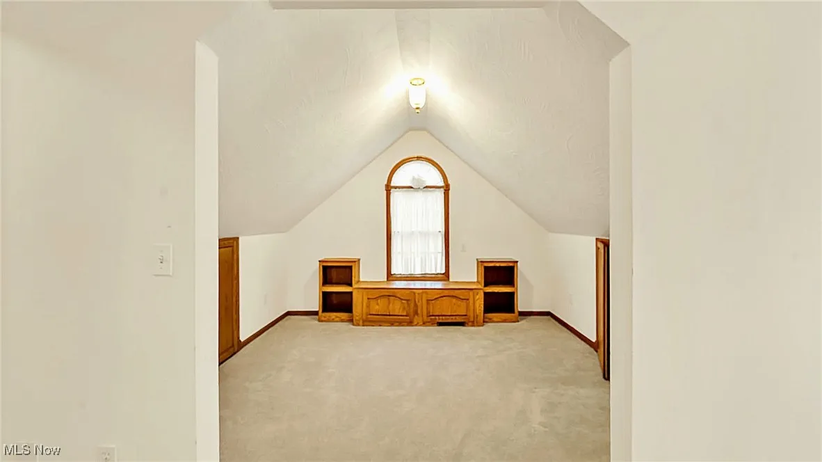 Primary suite sitting room with lofted ceiling and light carpet