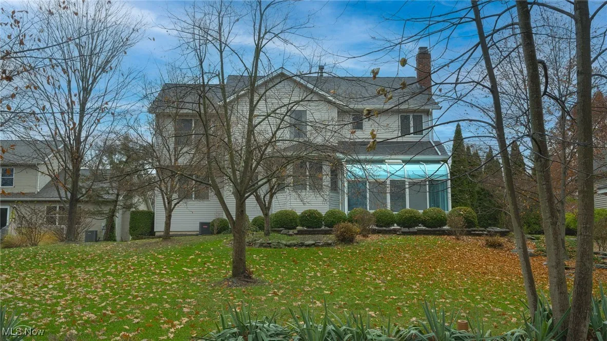 View of back facade featuring a back lawn and a chimney