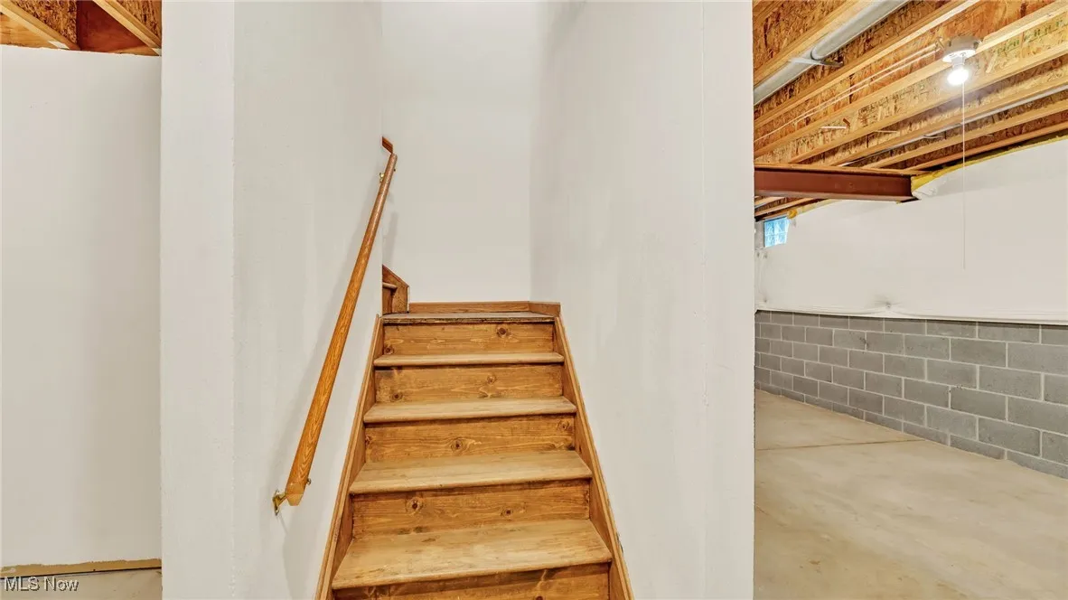 Basement staircase with unfinished concrete floors