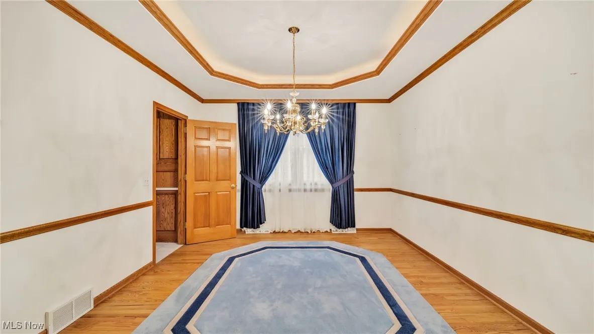 Dining room featuring a tray ceiling, wood finished floors, and a chandelier