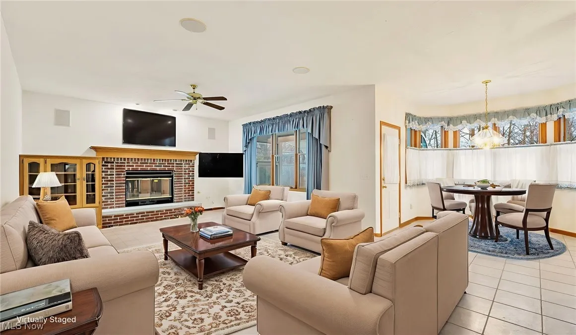Virtually staged family room featuring light floors, a ceiling fan, and a fireplace