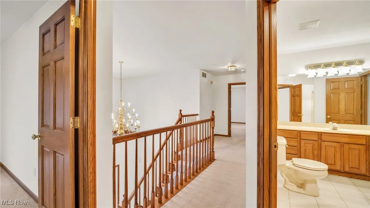 Hallway featuring a chandelier, an upstairs landing, light carpet