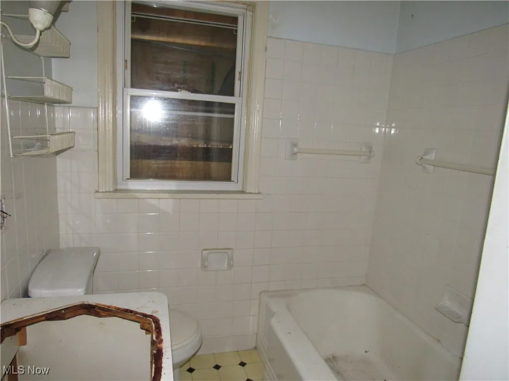 Bathroom featuring toilet and tile walls