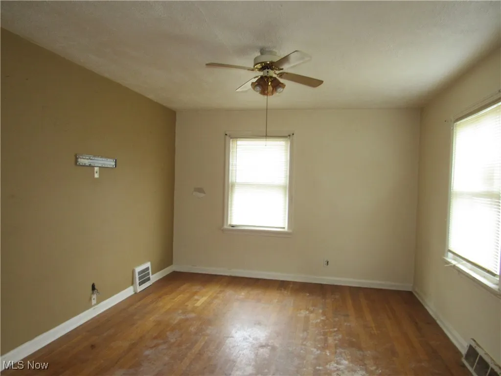 Empty room with wood finished floors, ceiling fan, and a textured ceiling