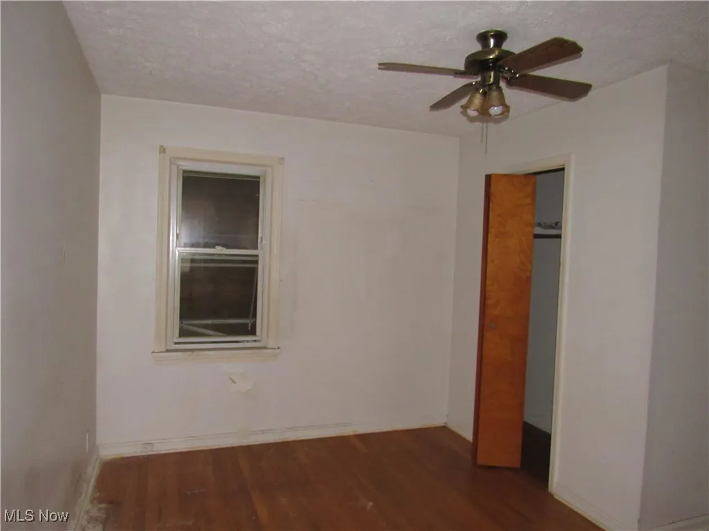 Unfurnished bedroom with dark wood-style floors, ceiling fan, a textured ceiling, and a closet